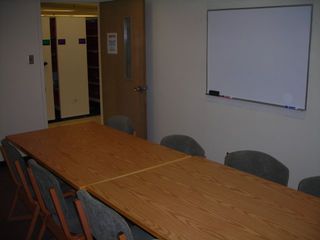 image of study room showing double table, 8 chairs white board on wall.