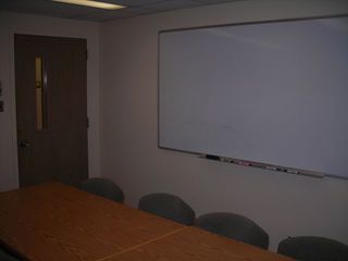 image of study room showing double table, 8 chairs white board on wall.